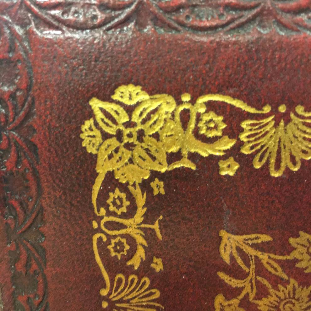 Red embossed leather book cover with gold inlay border design